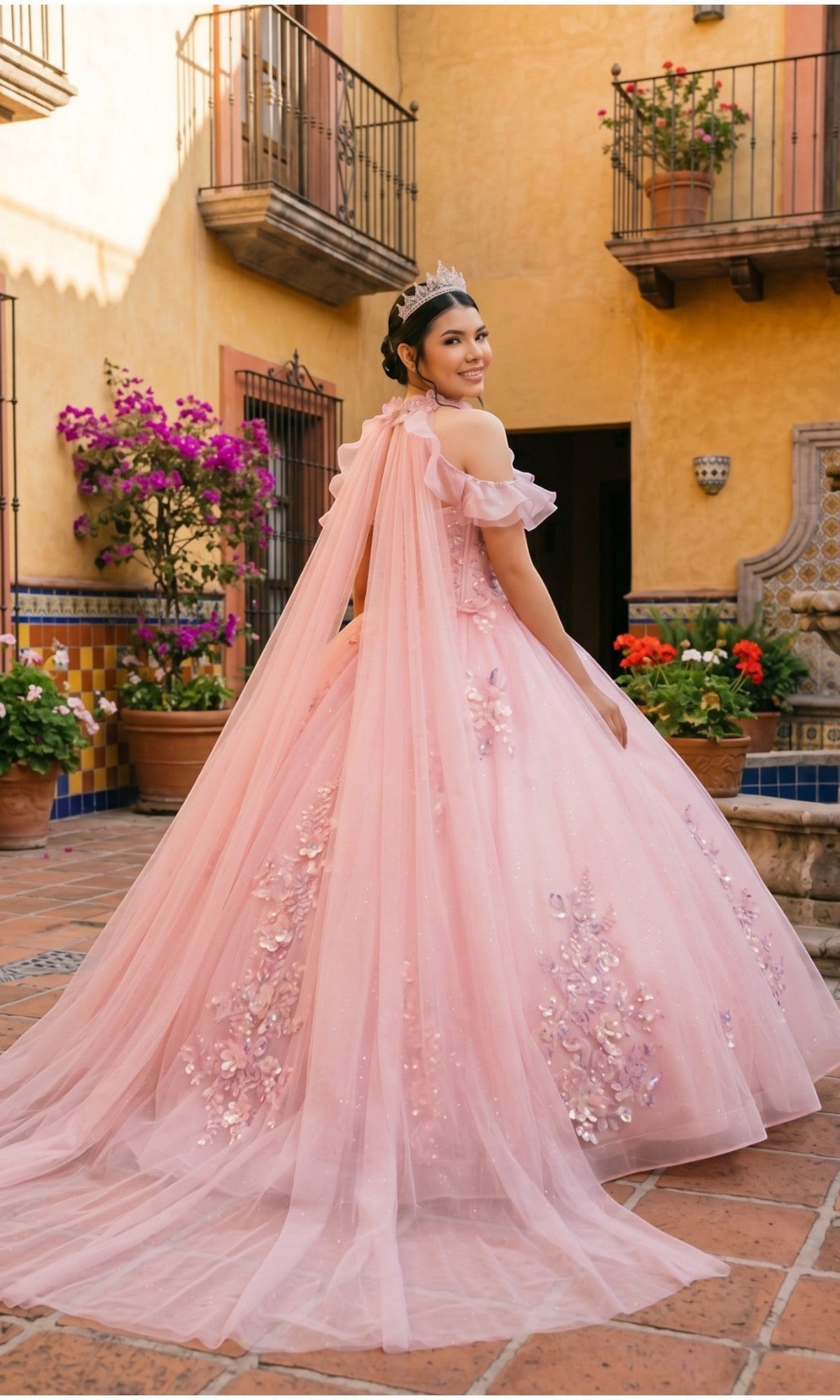 A young woman stands in a courtyard, smiling over her shoulder and wearing a tiara with the Quinceanera Dress 8585JQ By Cinderella Couture, featuring a floral lace corset.